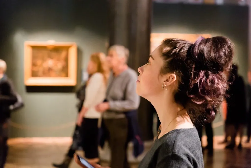 Unge kvinner ser på kunst på museet. Utflukt med gruppe