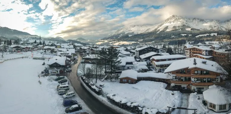 luftaufnahme von Ellmau in Tirol im Winter mit wolkigem blauen Abendhimmel