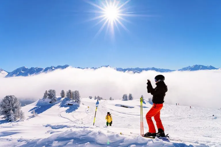 Kvinna skidåkare skidåkning i Zillertal Arena skidort i Tyrolen i Mayrhofen i Österrike i vinter Alperna. Flicka skidor i alpina berg med vit snö och blå himmel. Downhill kul på österrikiska snöiga backar.