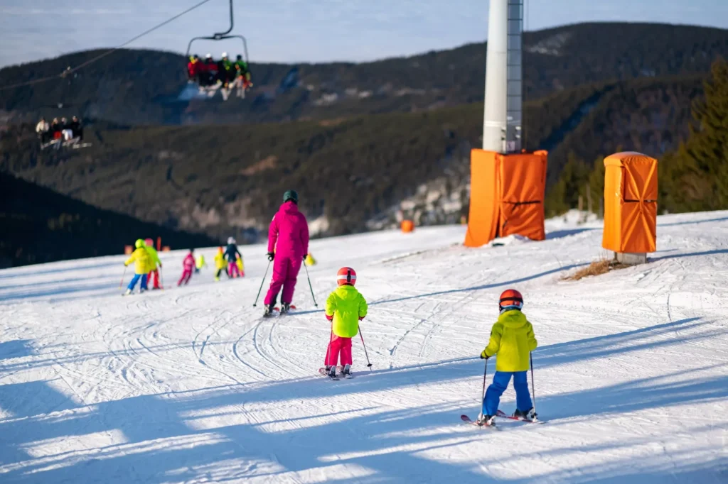 Grupa dzieci na stoku narciarskim podczas lekcji w szkole narciarskiej.