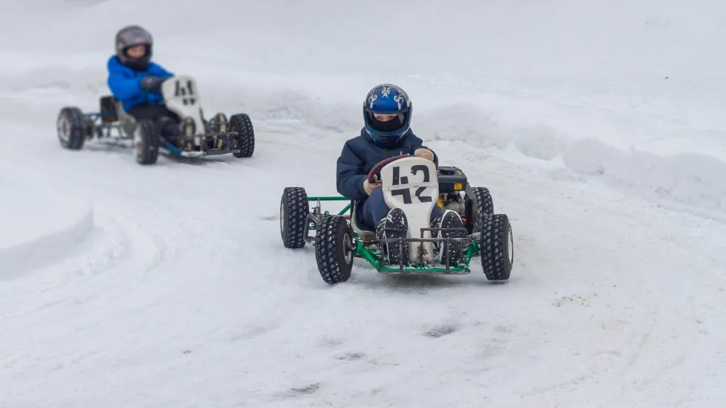 Barnens karting tävlingar på vintern. Tonåringar kör genom snön i bilar för barn.