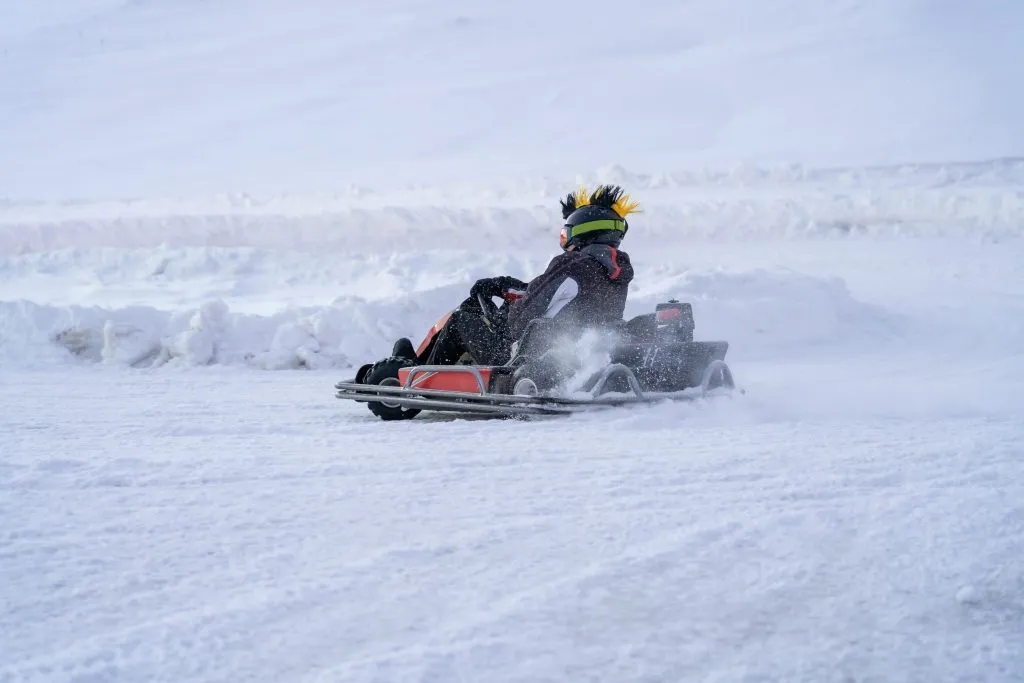 Go karting su pista ghiacciata in inverno. Pilota adulto di kart in azione su pista ghiacciata all'aperto