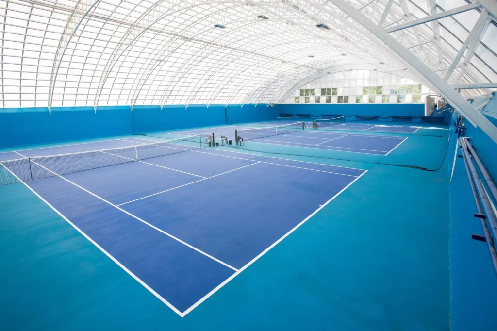 Bakgrundsbild av modern tennisbana inomhus i blå färger, kopieringsutrymme