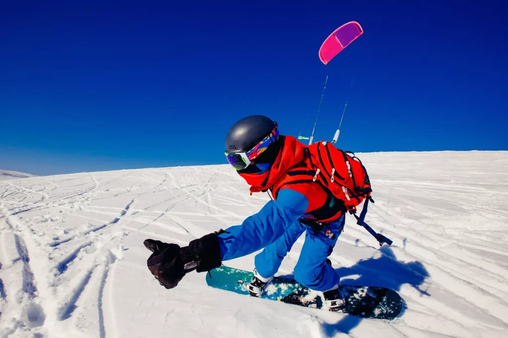 Snowboardzista z latawcem na świeżym śniegu w zimie w tundrze Rosji na tle czystego błękitnego nieba. Teriberka, Półwysep Kola, Rosja. Koncepcja sportów zimowych snowkite.