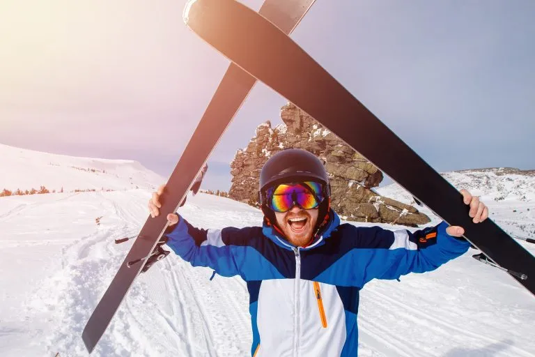 Selfie Guy sportsman goes on normal skiing on ski slope with action camera.