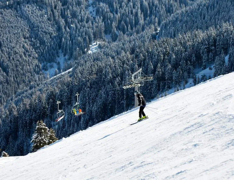 Folk på ski nedover bakken. Skiløype på en solrik vinterdag i fjellskianlegget Alpbachtal, Wildschönau, Østerrike.