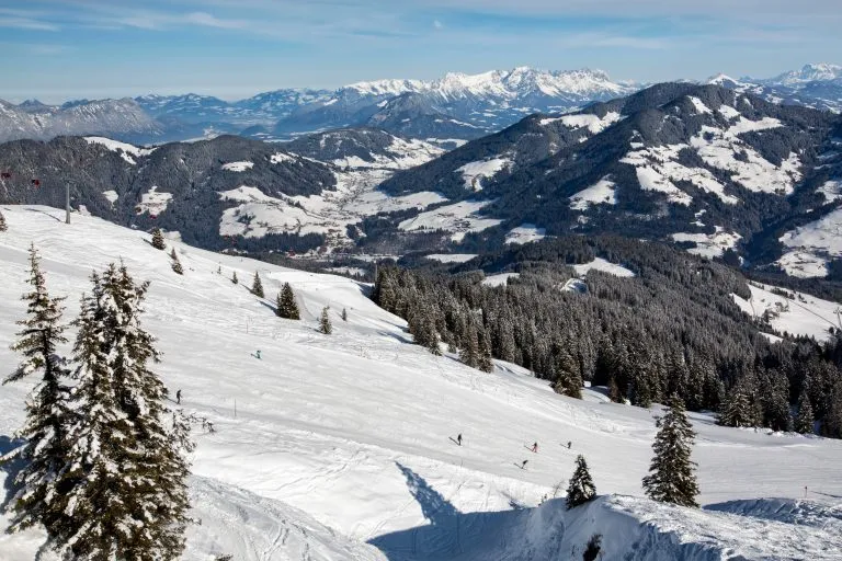 Panoramic view of people skiing down the slope and oberau Wildschönau in winter sunny day at the mountain ski resort of Alpbachtal, Wildschönau, Austria