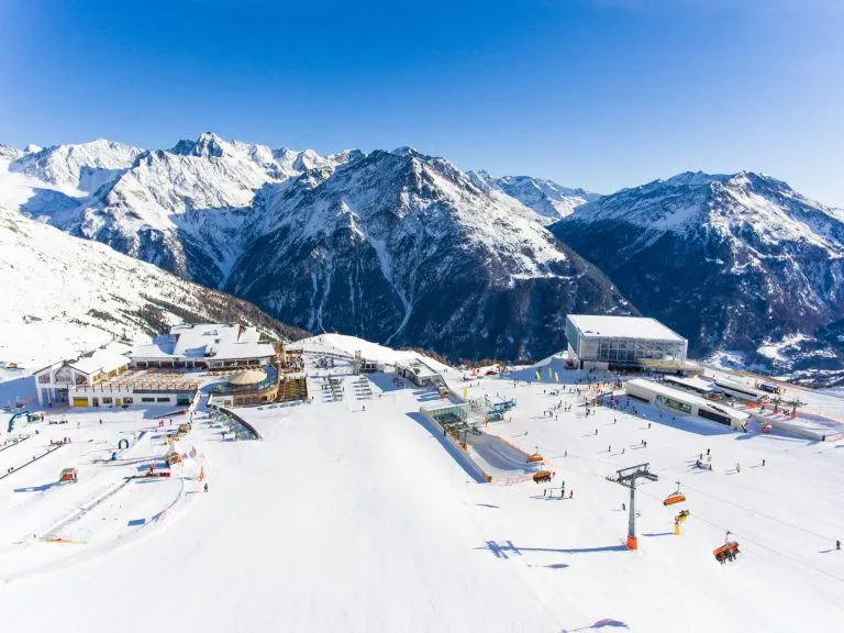 Skidort i Alperna med skidlift och människor som åker skidor i backen