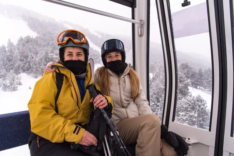 Two young blonde girls on a gondola of a ski resort in winter