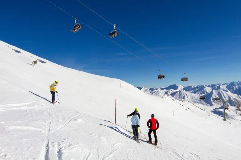 Quattro sciatori sulla pista da sci