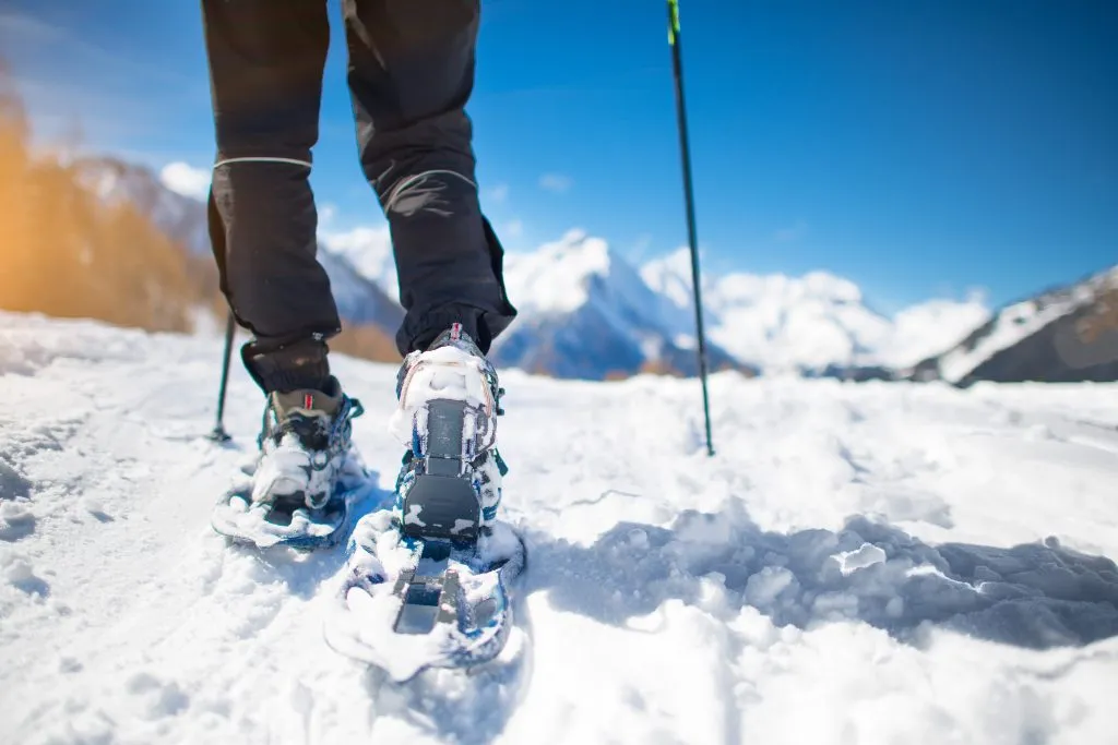 Camminare con le ciaspole nella neve durante le vacanze in montagna