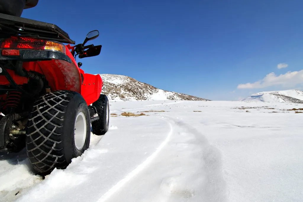 röd fyrhjuling i snöigt bergslandskap